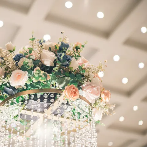 A hanging crystal chandelier crowned with peach and white roses and greenery