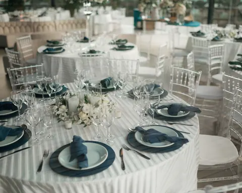Round tables with striped white linens, navy napkins and clear chairs