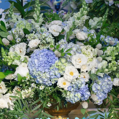 A large arrangement of blue hydrangea, white roses and greenery