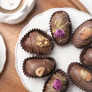 Chocolate-covered stuffed dates beside a cup of coffee