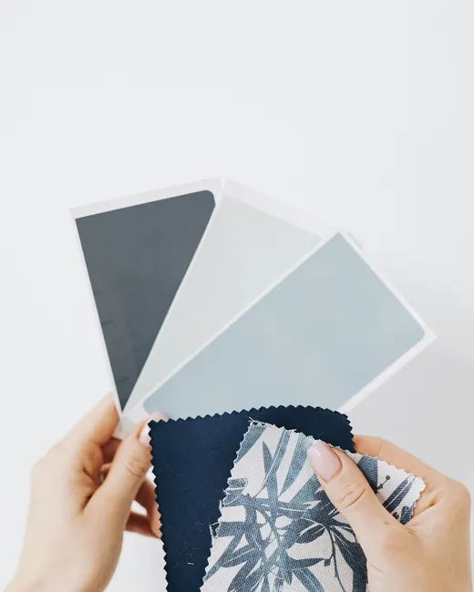 Two hands comparing fabric swatches in blues and greys